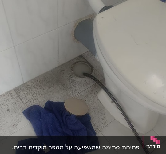 אסלה עם צינור ניקוז, מגבת כחולה על הרצפה